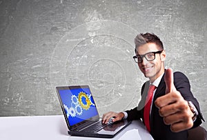 Satisfied business man working on laptop and making ok sign