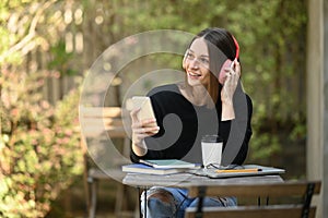 Satisfied caucasian woman listening to music on headphone and mobile phone at out door