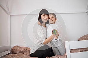 Satisfied caucasian young lady embracing preschooler girl after combing her hair