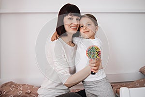 Satisfied caucasian young lady embracing preschooler girl after combing her hair