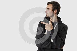 Satisfied caucasian young man pointing at blank space. Isolated on white background. Advertisement concept