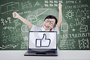 Satisfied child raise hands with an OK sign on laptop