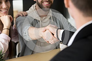 Satisfied couple handshaking realtor closing successful deal