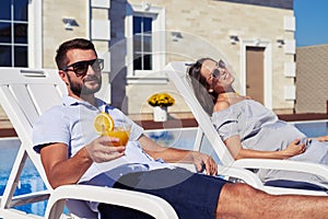 Satisfied couple relaxing in front of modern house with pool