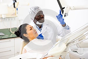 Satisfied dentist showing female patient x-ray of teeth on computer screen