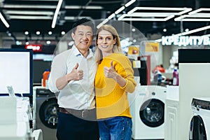 Satisfied diverse couple of shoppers Asian man and woman smiling and looking at camera