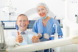 Satisfied patient visiting dentist giving thumbs up