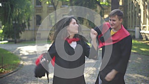 Satisfied excited graduates dancing on sunny morning at university campus smiling. Portrait of happy positive Caucasian