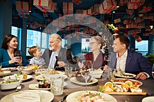 Satisfied family enjoying Christmas dinner together in cozy restaurant