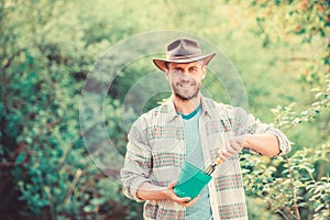 Satisfied farmer hold garden rake and flower pot. muscular ranch man in cowboy hat. farming and agriculture. Garden