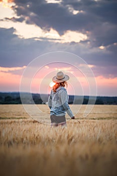 Satisfied farmer is looking at barley field in her farm