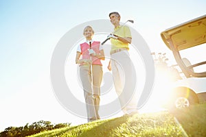 Satisfied feeling of a game well played. Attractive elderly couple on the green with the sun setting behind them.