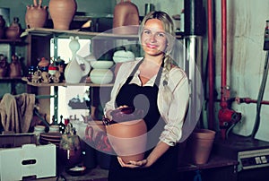 Satisfied female artisan having ceramics in workshop