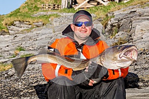 Satisfied fisherman with glasses. holding big fish on his hands.