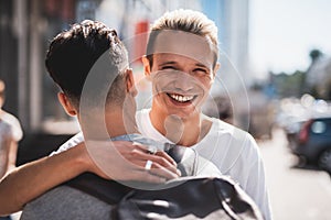 Satisfied friends embracing during meeting at street