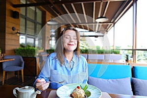 Satisfied girl eating dessert at restaurant .