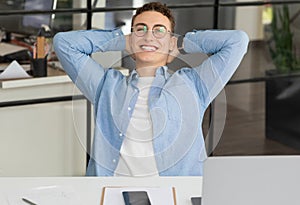 Satisfied handsome millennial caucasian guy manager in glasses with laptop rest at table