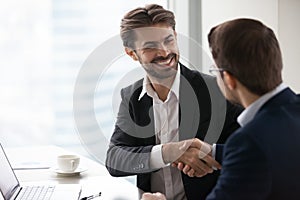 Satisfied happy businessman in suit handshake business partner making deal