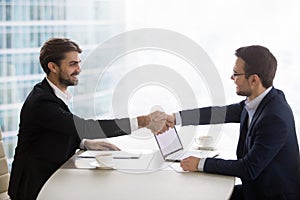 Satisfied happy businessmen shake hands at business office meeting