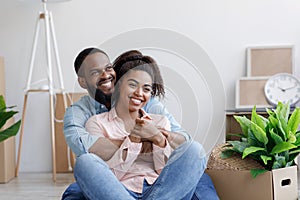 Satisfied happy millennial african american loving family, husband and wife hugging, relaxing in new apartment