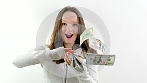 satisfied happy teenage girl scatters 100 dollar bills in different directions slow motion video on a white background