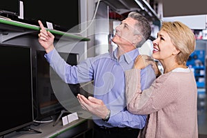 Satisfied husband and wife choose for themselves TV in center of electronics photo