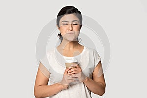 Satisfied Indian girl holding paper cup coffee, enjoying hot beverage