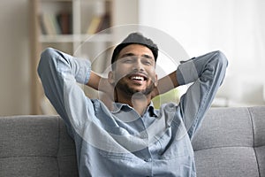 Satisfied Indian guy enjoy pleasant relaxation alone indoor