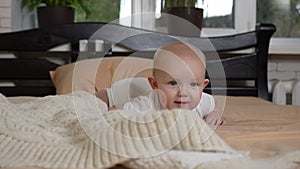 A satisfied little eared baby is trying to crawl on the bed