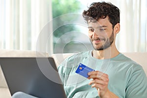 Satisfied man buying online using credit card and laptop