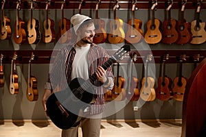 Satisfied man musician glad to choose new acoustic guitar for performance