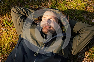 satisfied man sleeping and resting on green forest moss. nature escape and tranquility. stress relief and mental health
