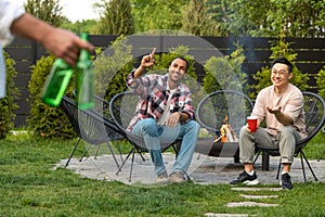 Satisfied men friends enjoying drinking beer during summer picnic