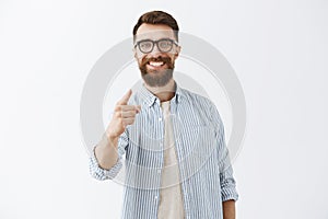 Satisfied and pleased handsome male entrepreneur feeling delighted with good work of employee pointing with index finger