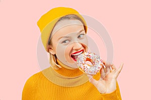 Satisfied pretty girl eating donut on pastel pink background