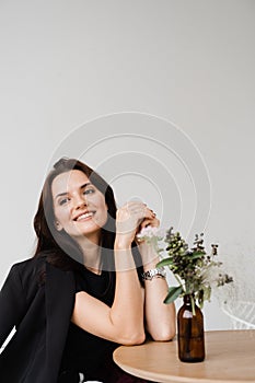 Satisfied successful girl enjoying her lifestyle and dreaming in white office at break. Young business woman is smiling