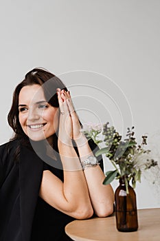 Satisfied successful girl enjoying her lifestyle and dreaming in white office at break. Young business woman is smiling