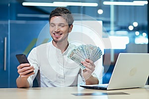 Satisfied and successful young man received a big money prize. He holds money in his hands, calls friends, rejoices, brags.