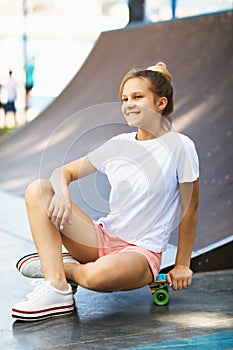 Satisfied teen girl resting on a skateboard while riding in the park