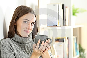 Satisfied teen holding coffee mug looks at camera