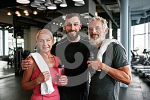 Satisfied trainer with elderly sporty couple at gym