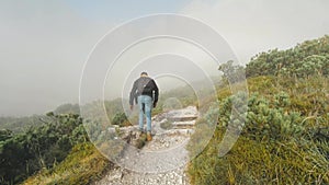 Satisfied traveler man climbing along a hiking route to the top of mountain, Alps, Austria