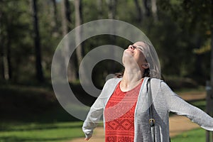 Satisfied woman breathing fresh air in the forest