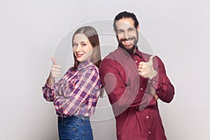 Satisfied woman and man standing together showing thumbs up, like gesture, positive feedback