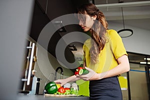 Satisfied woman standing in the kitchen picking vegetables