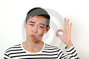 Satisfied young Asian man giving the okay sign and looking at ca