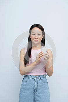 A satisfied young asian woman drinking milk from the glass isolated over white background