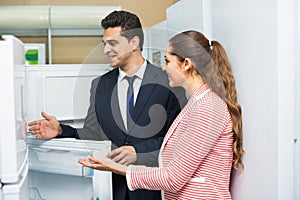 Satisfied young customers looking at large fridges