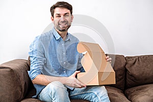 Satisfied young smiling man receiving package from online store