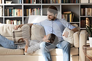 Satisfied young woman using laptop, lying on man laps